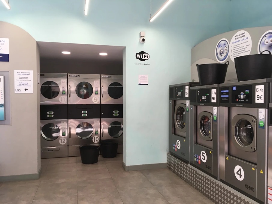 Stacked dryers, 8 kg, 13 kg and 19 kg washers and free Wi-Fi corner inside the LQS laundromat on Carrer de Casanova