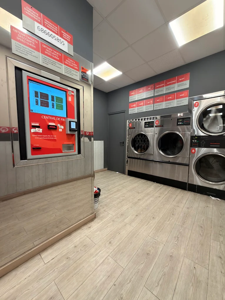 Speed Queen laundromat interior at Carrer del Carme 5 with central payment kiosk and row of washers