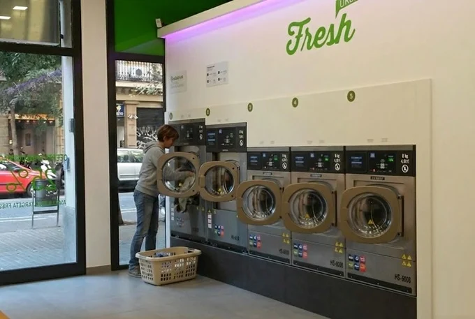 Fresh laundromat interior on Carrer de Londres, Eixample Barcelona with row of Girbau washers