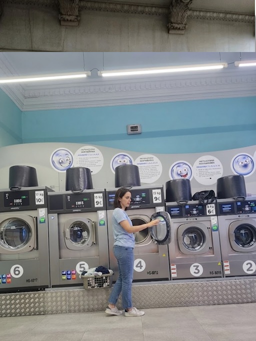 Customer loading a washer inside the LQS laundromat at Carrer de Casanova 172, Barcelona